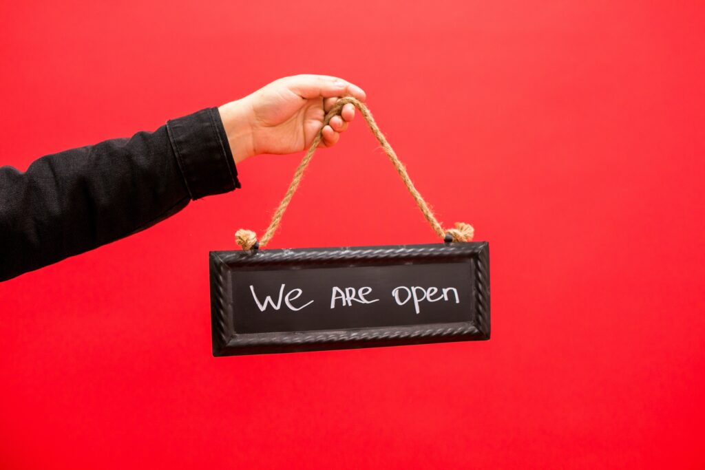 A Person Holding a Hanging Sign saying "We're open"